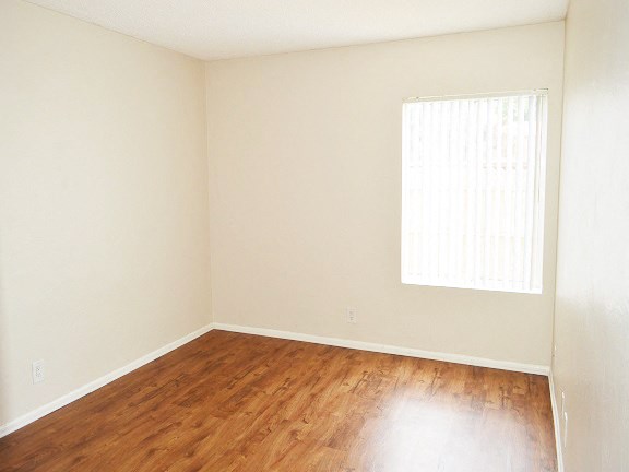 an empty room with wood floors and a window