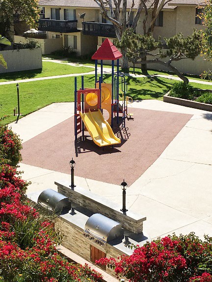 a playground with a yellow swing set in a park