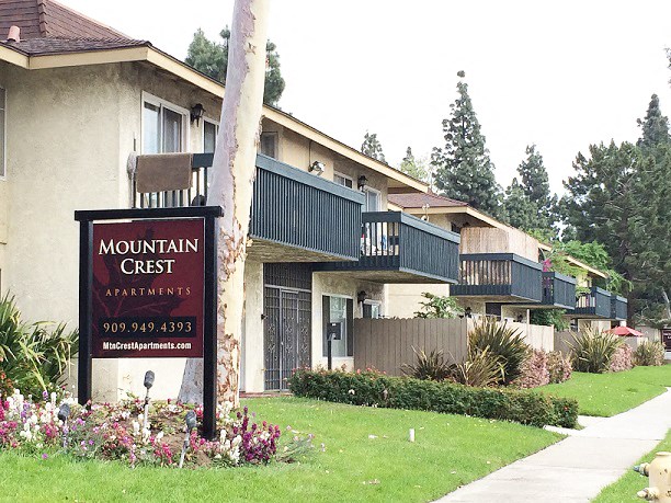 a mountain crest apartments building with a sign in the grass