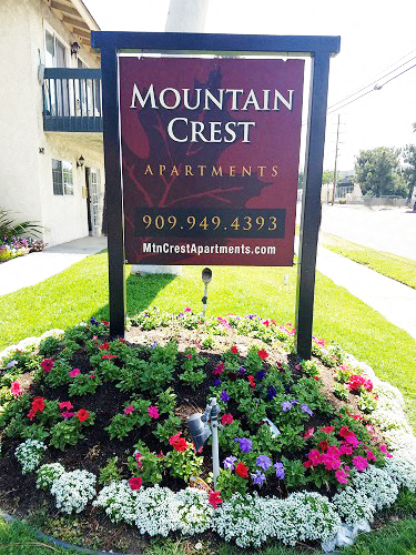 a sign for mountain crest apartments in front of a flower garden