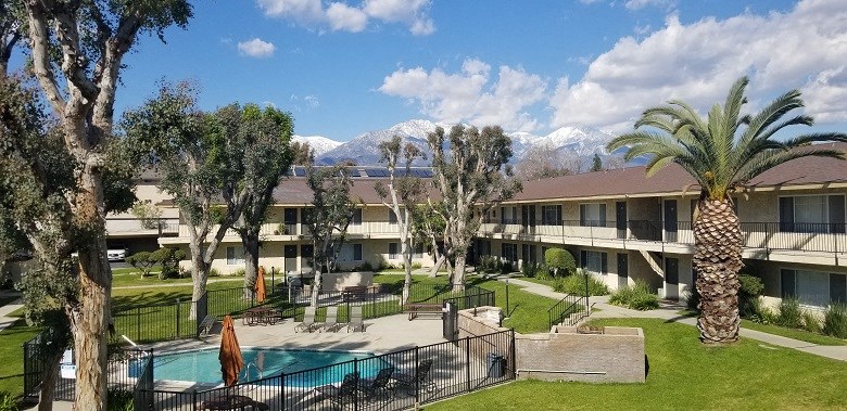 a hotel with a pool and palm trees in front of it