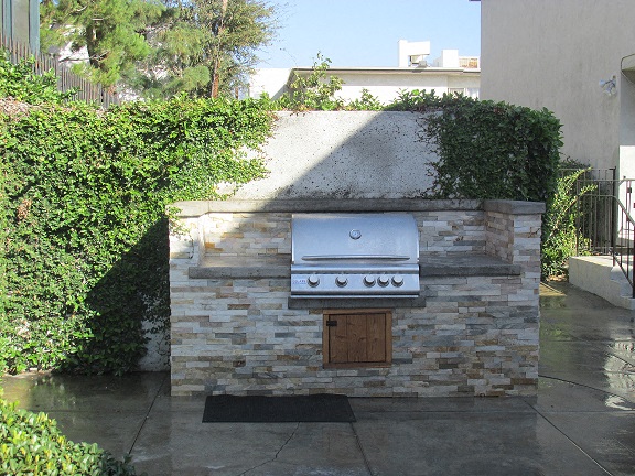 a barbecue grill on a stone wall in a backyard