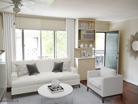 A living room with a white couch, a white coffee table, and a white chair.