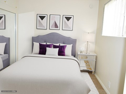 A bedroom with a large bed and a nightstand with a lamp.
