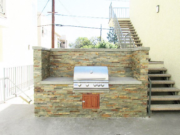 a barbecue grill on a brick wall next to stairs