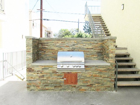 a barbecue grill on a brick wall next to stairs