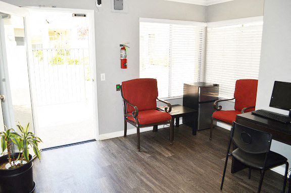 a living room with red chairs and a piano