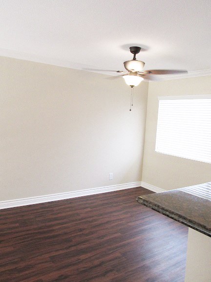 an empty bedroom with a ceiling fan and a window