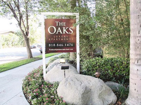 a sign for the luxury apartments in front of a rock
