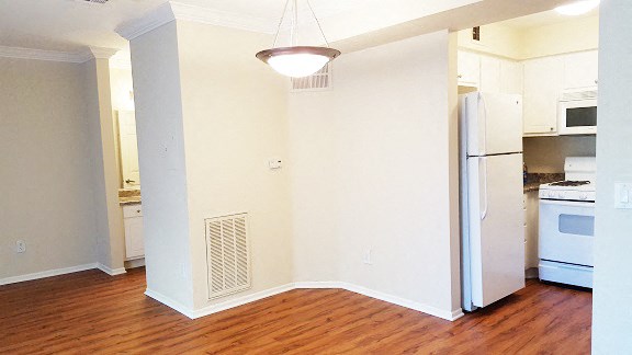 an empty kitchen with a wood floor and a refrigerator
