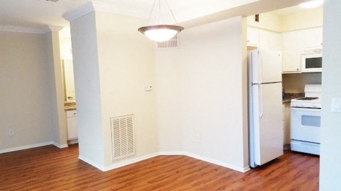 an empty kitchen with a wood floor and a refrigerator