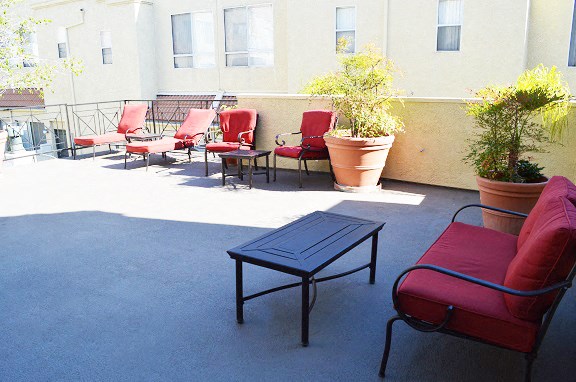 a patio with red chairs and a blue table