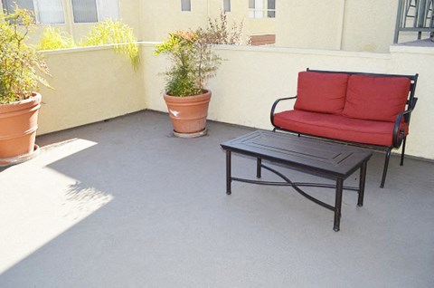 a patio with a couch and a table and potted plants