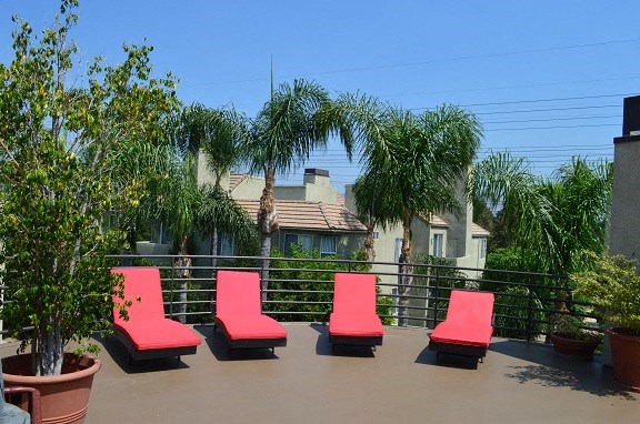 four red lounge chairs on a balcony with houses