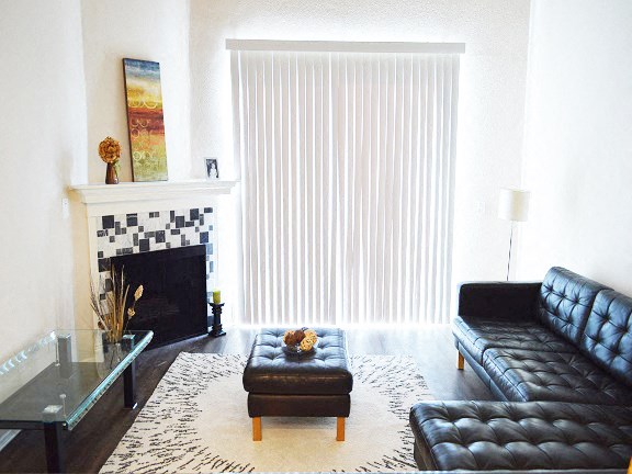 a living room with black leather furniture and a fireplace