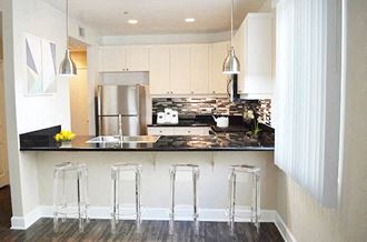 a kitchen with white cabinets and a bar with three stools