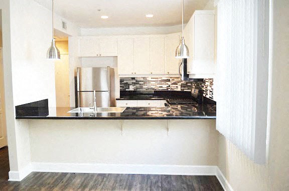 a kitchen with white cabinets and a black counter top