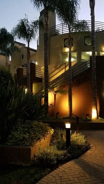 a house is lit up at night with palm trees