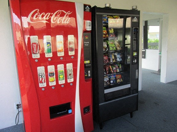 a red coke vending machine next to a black vending machine