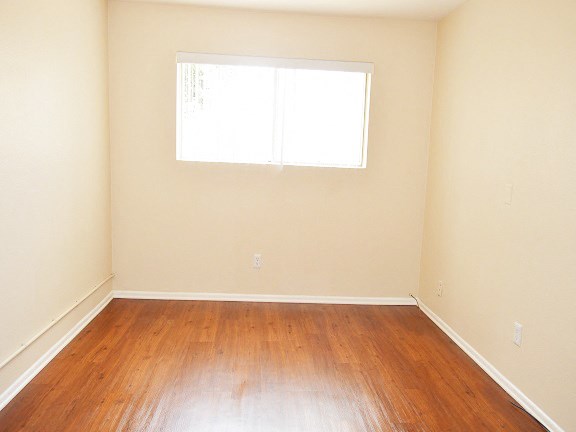 an empty room with wooden floors and a window