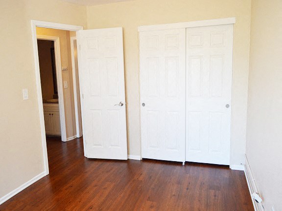 an empty room with three doors and a wood floor