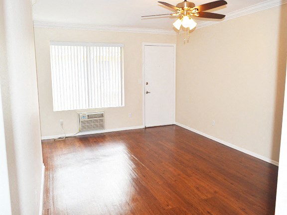 an empty living room with wood floors and a ceiling fan