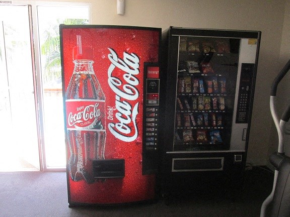 a coca cola refrigerator next to a coke machine