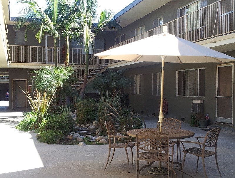 a patio with tables and an umbrella in front of a building