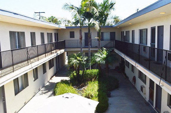 the courtyard of an apartment building with balconies and palm trees