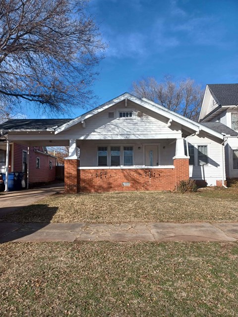 a white house with a brick wall and a porch
