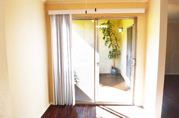 a living room with a sliding glass door and a potted plant