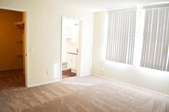 an empty room with three windows and a door to a bathroom