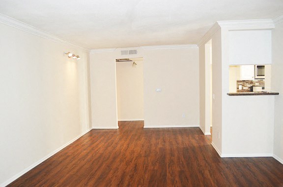an empty living room with a wood floor and white walls