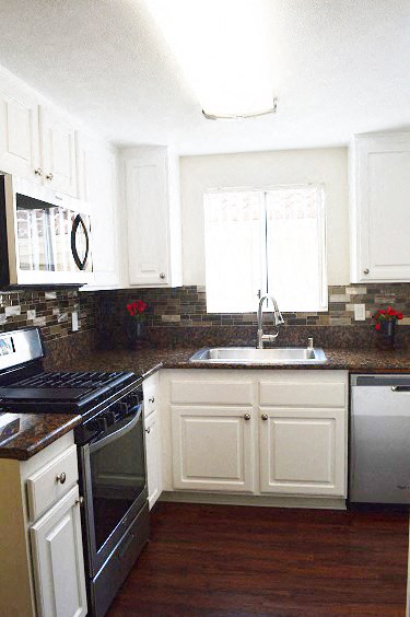 a kitchen with white cabinets and a stove and a sink