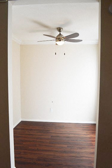 an empty room with a ceiling fan and wood floors