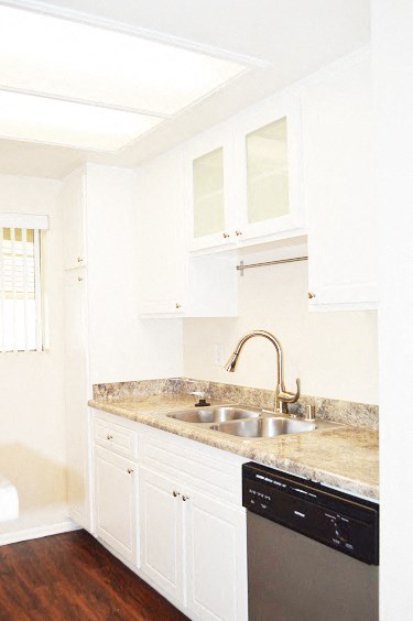 an empty kitchen with white cabinets and a sink