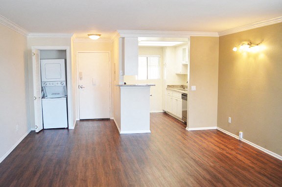 an empty living room and kitchen with a wood floor