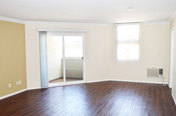 an empty living room with wood floors and a sliding glass door