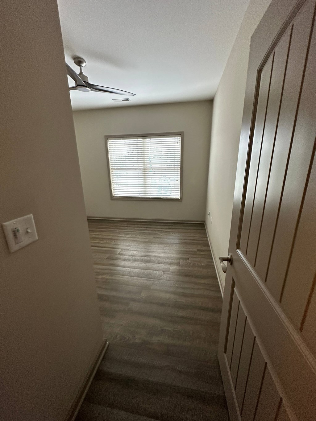 a hallway with a door and a window and a ceiling fan