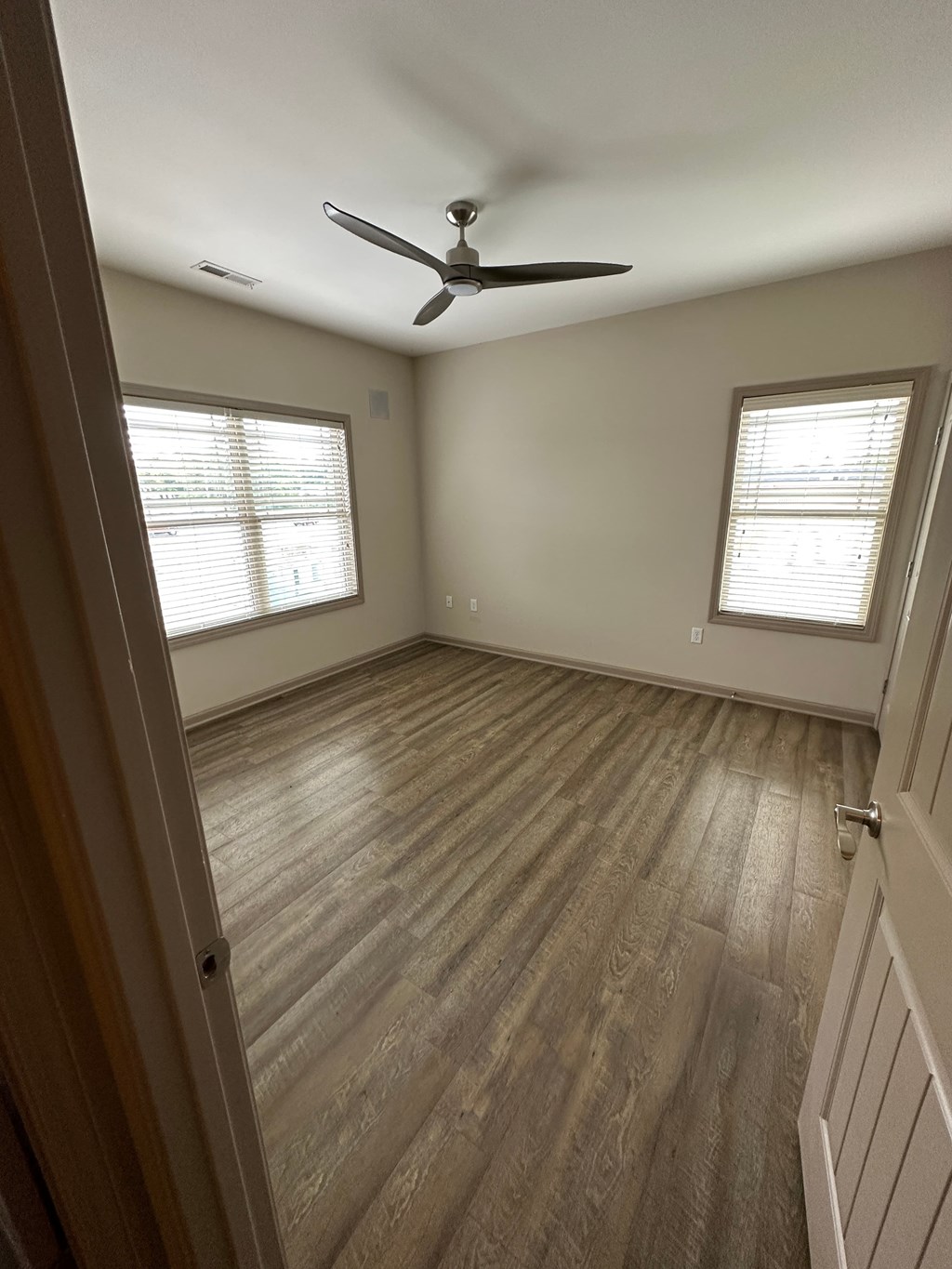 an empty room with a ceiling fan and wood floors