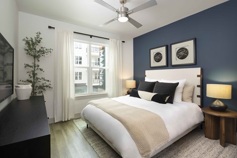Stylish primary bedroom with large bright windows and elegant furniture at MAA Nixie Luxury apartments in Durham, NC