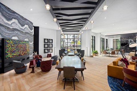 Spacious clubhouse with wood floors and art with multiple seating and lounge areas at MAA Nixie luxury apartments in Durham, NC