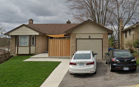 A white car is parked in front of a house with a garage.