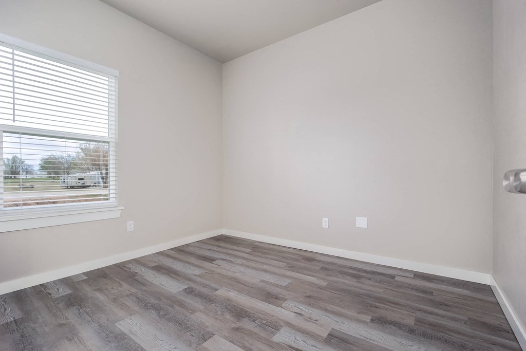 an empty room with wood flooring and a window