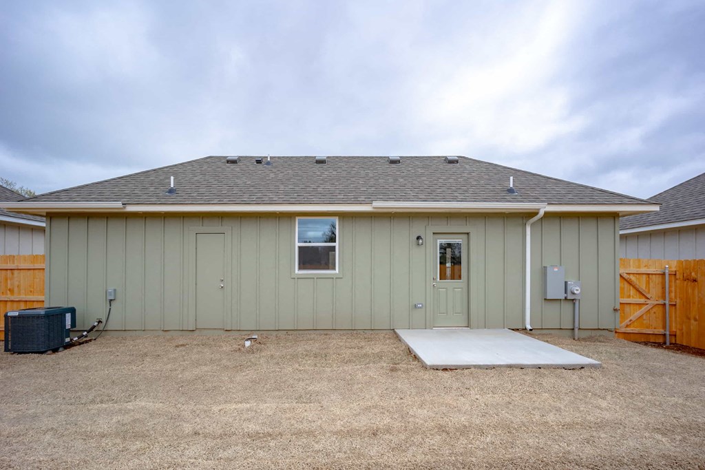 the front of a green house with a yard and a driveway