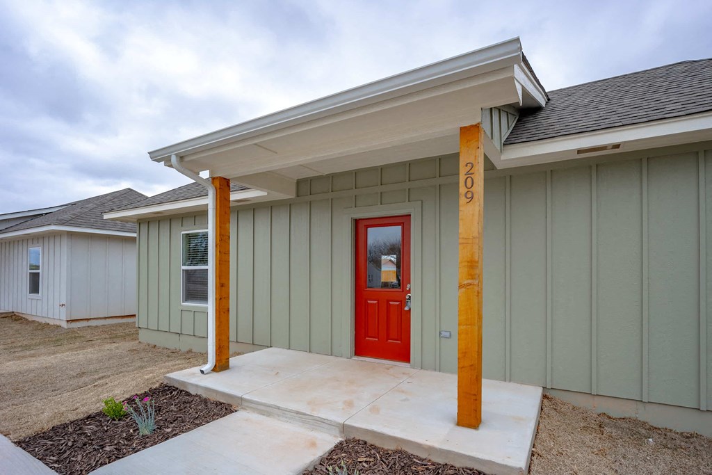 the front porch of a house with a red door