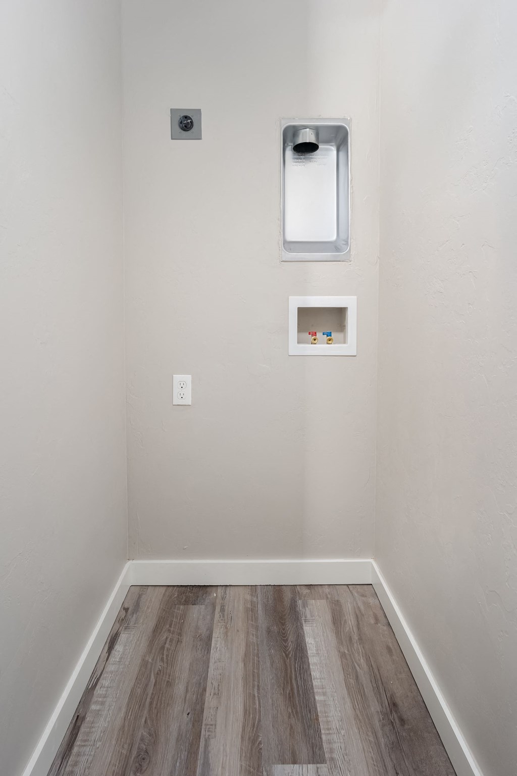 an empty room with white walls and wood flooring and a window