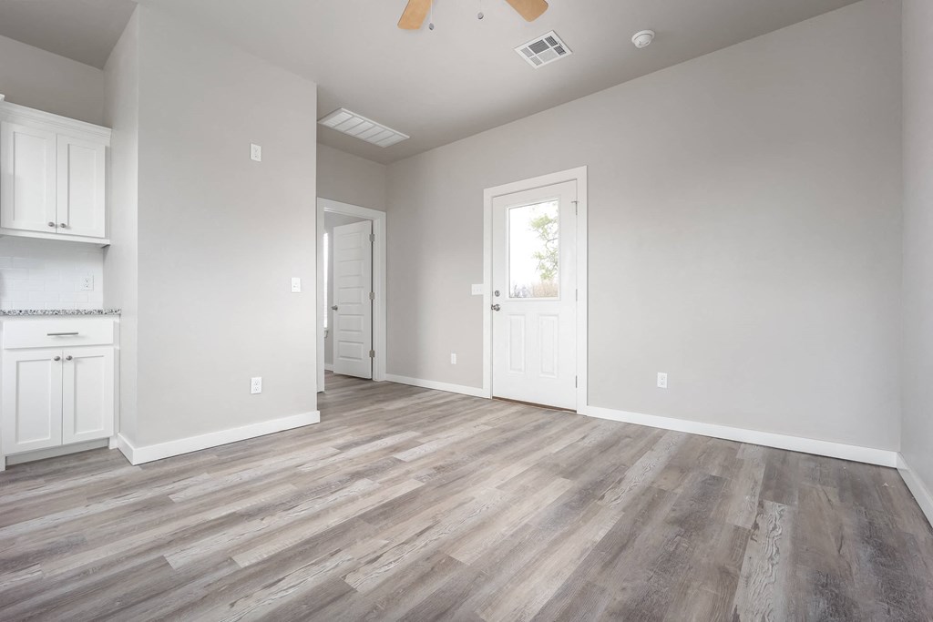 an empty living room with white walls and wood floors