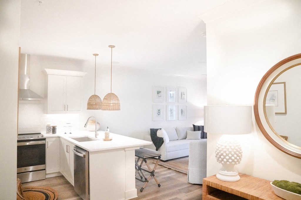 a kitchen and living room with white walls and wood floors
