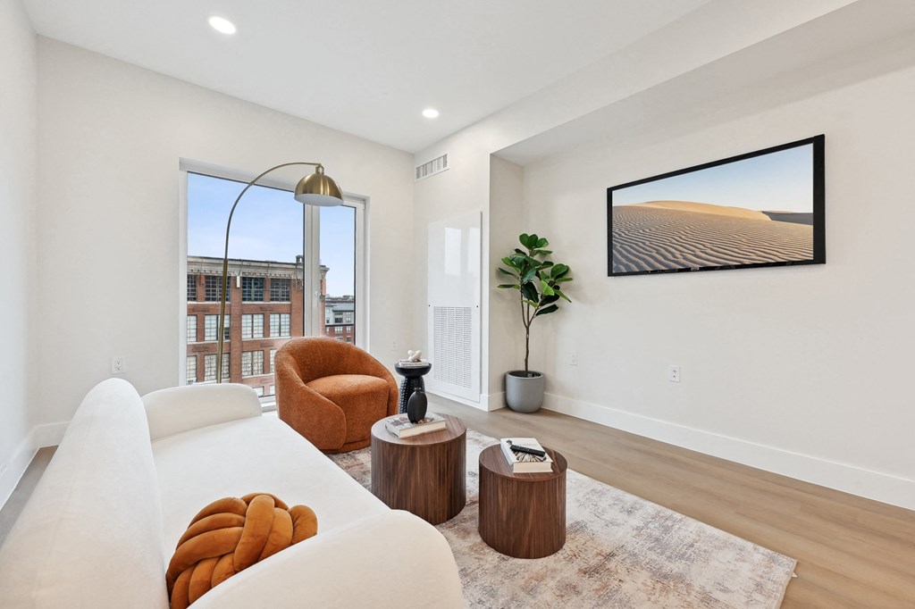 a living room with a white couch and a chair and a window